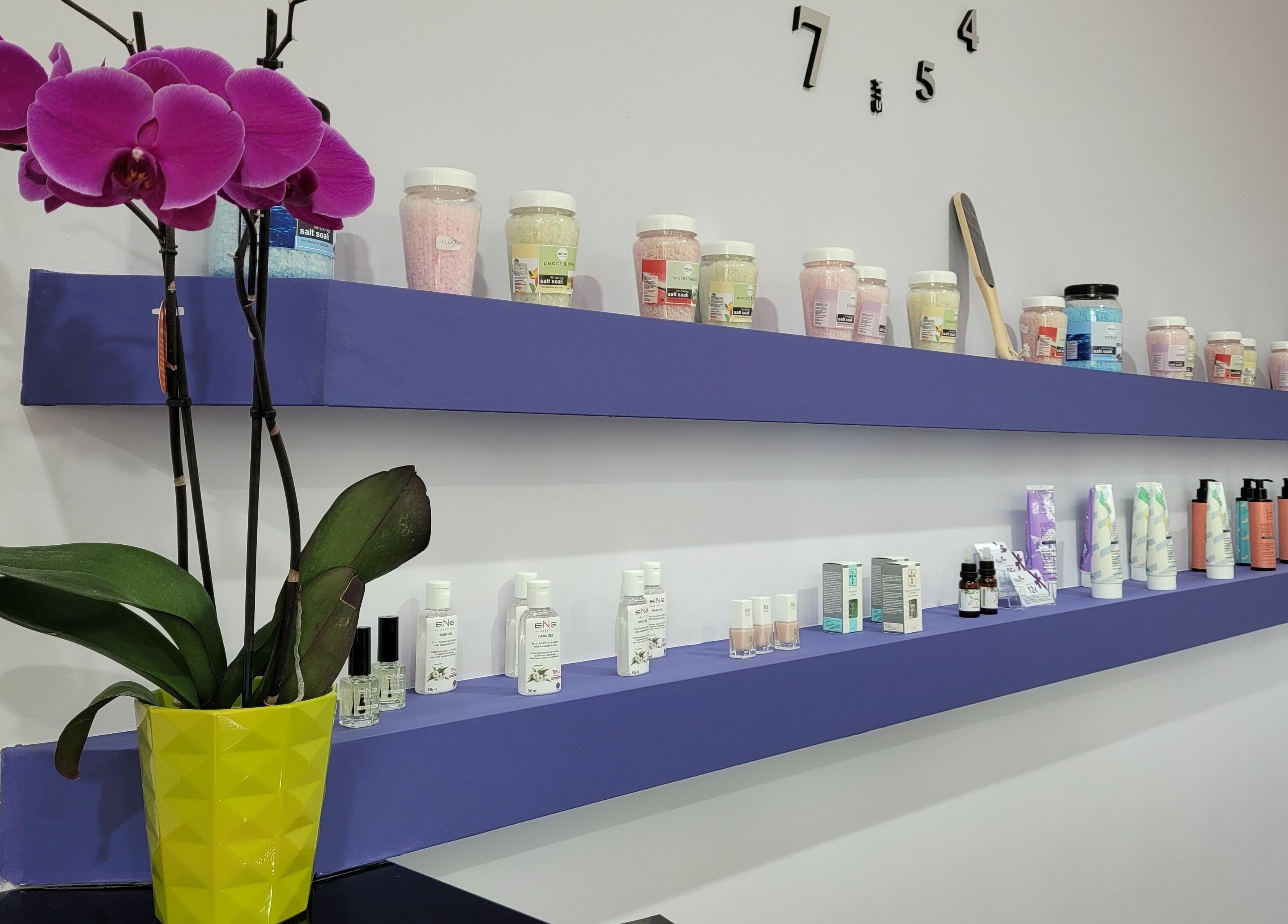 Βιολετί ράφια με προϊόντα ομορφιάς και ορχιδέα στο Nails 4 You, Παλλήνη, GR.