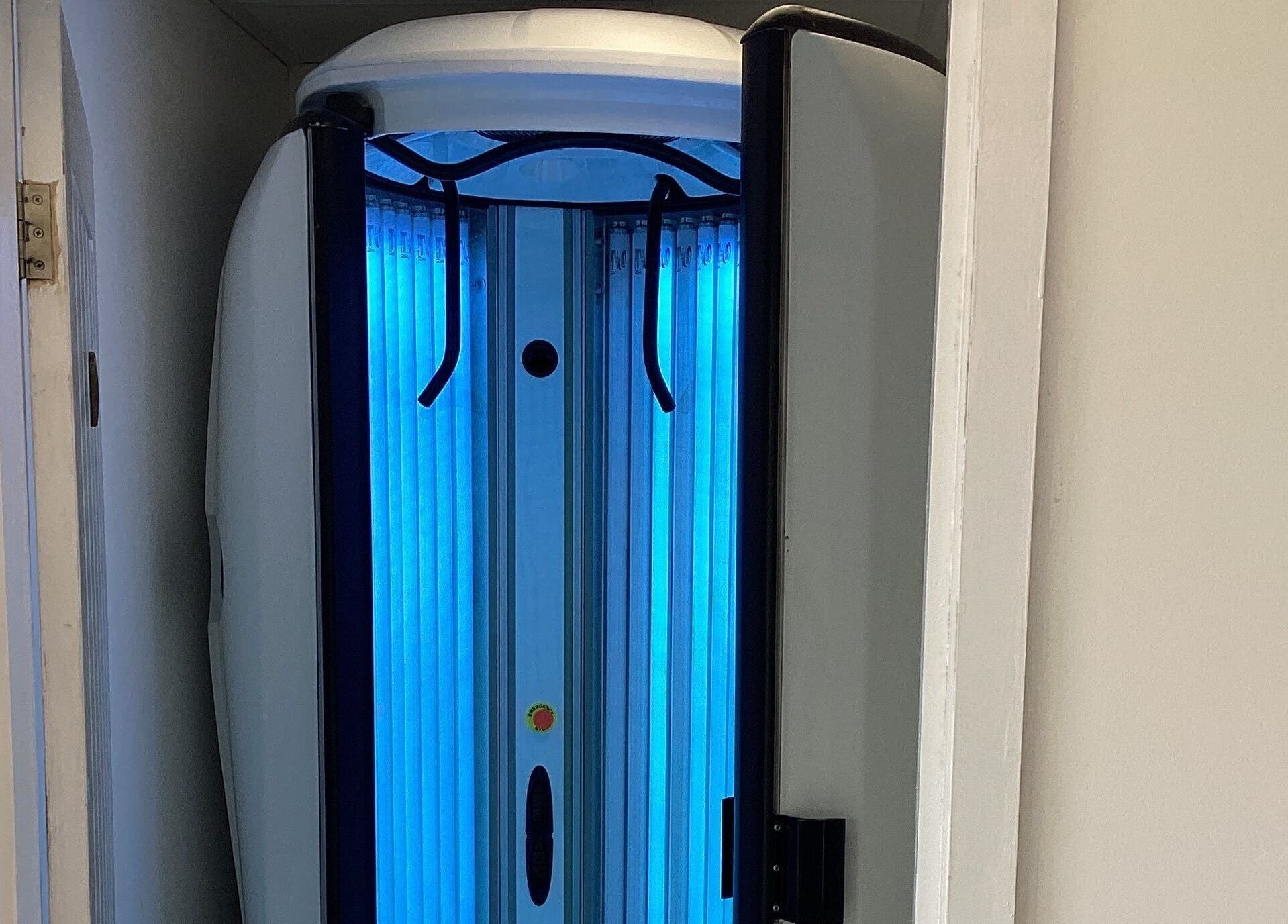 Tanning booth in Bronzed of Broadstone, Poole, England, GB, showcasing blue light ambiance for optimal tanning experience.