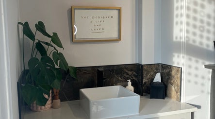 Chic washbasin at BEAUTY RACK, Skipton, England with lush plant and motivational art on the wall.