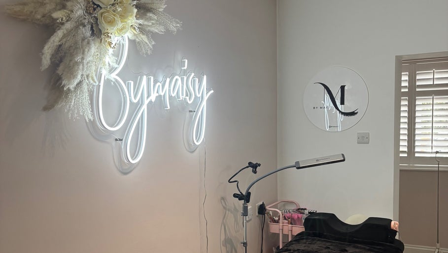 Chic ByMaisy beauty space in Bexleyheath, England, GB featuring illuminated signage and wellness equipment.