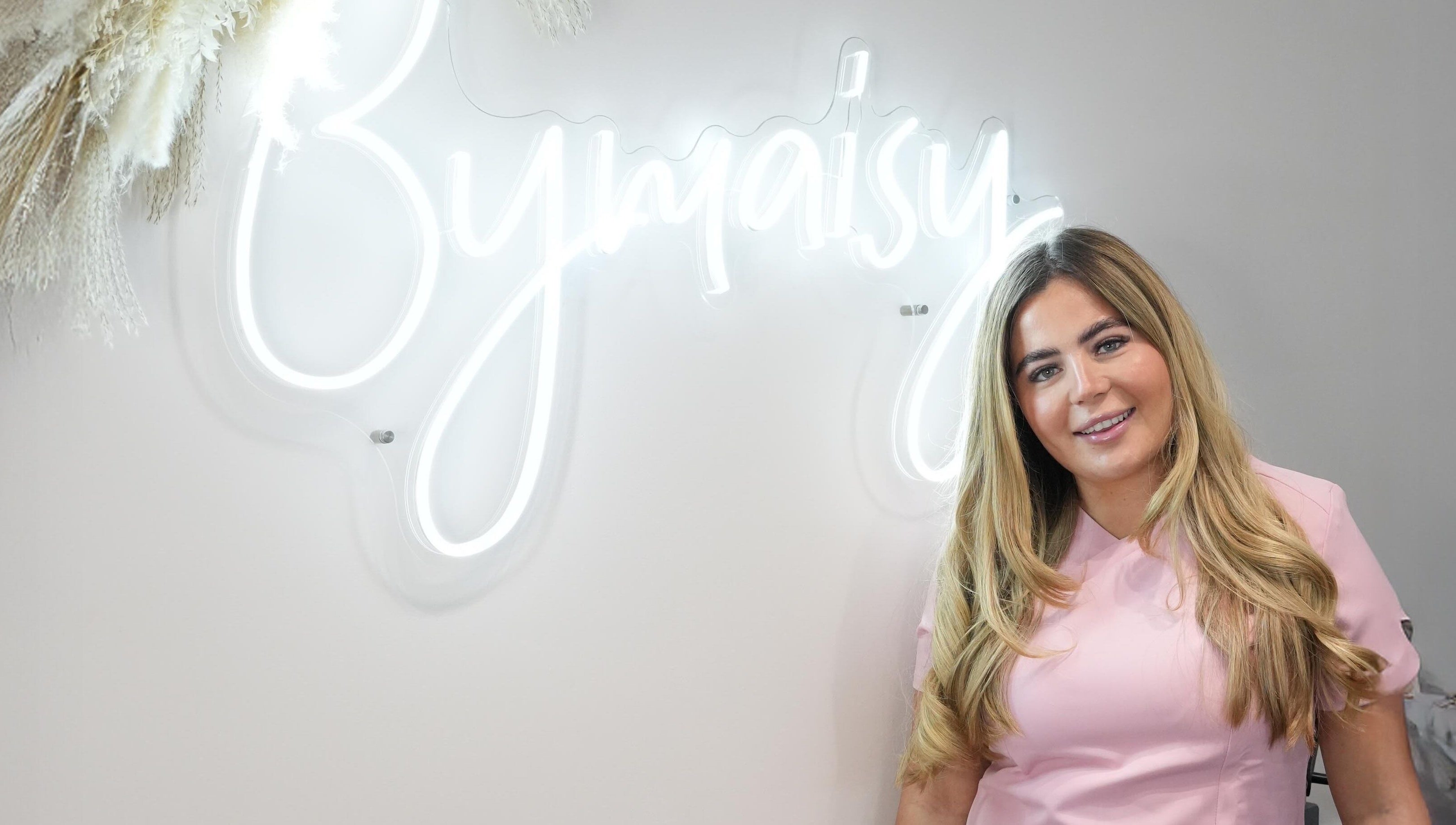 Smiling professional at ByMaisy in Bexleyheath, England, GB, with neon sign backdrop.