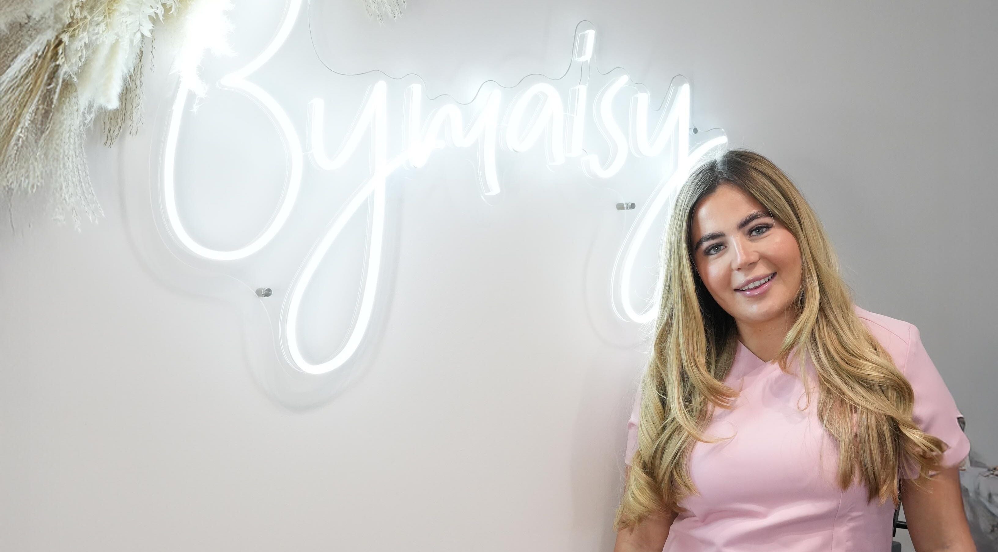 Smiling professional at ByMaisy in Bexleyheath, England, GB, with neon sign backdrop.