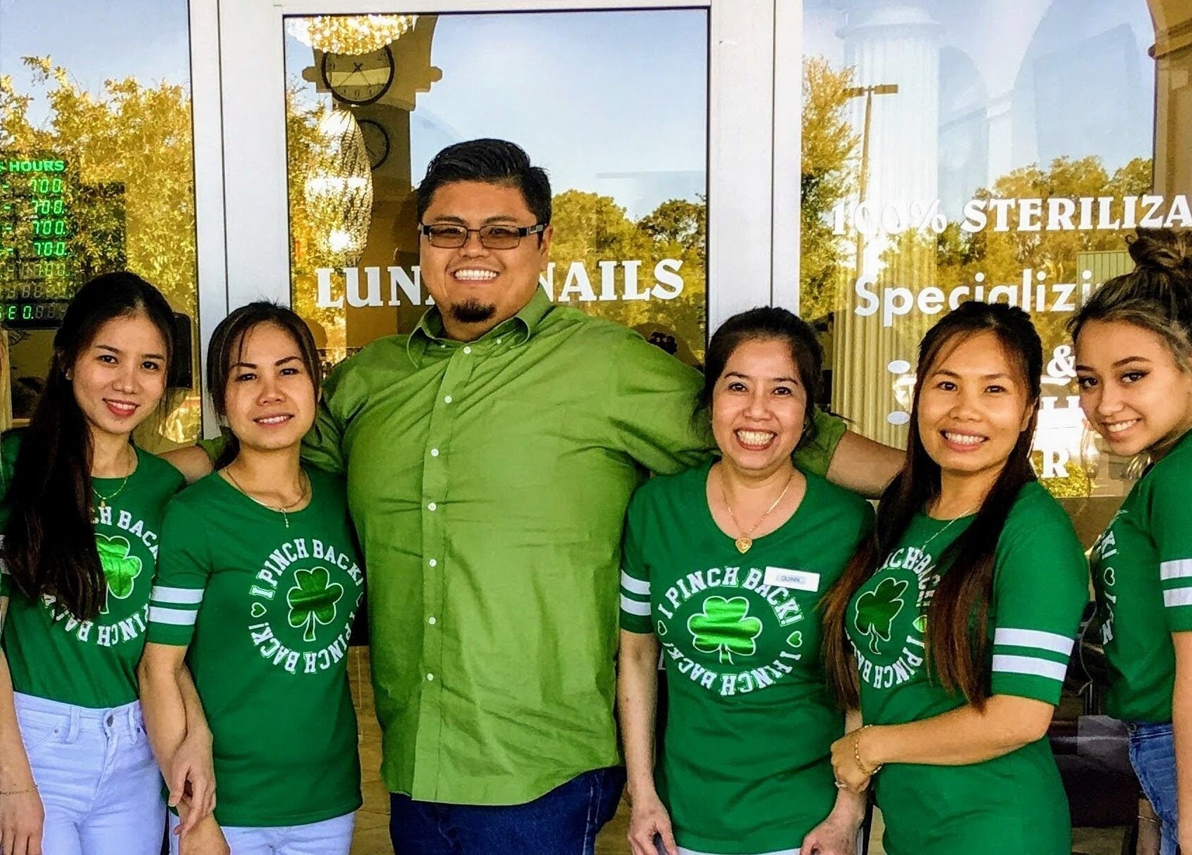 Team at Lunar Nails in The Villages, Florida, US, celebrating in matching green shirts with smiles.