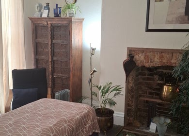 Relaxing massage room at Shass Therapy Massage in Cheltenham, England, GB with cozy decor and fireplace.