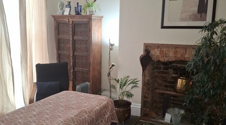 Relaxing massage room at Shass Therapy Massage in Cheltenham, England, GB with cozy decor and fireplace.