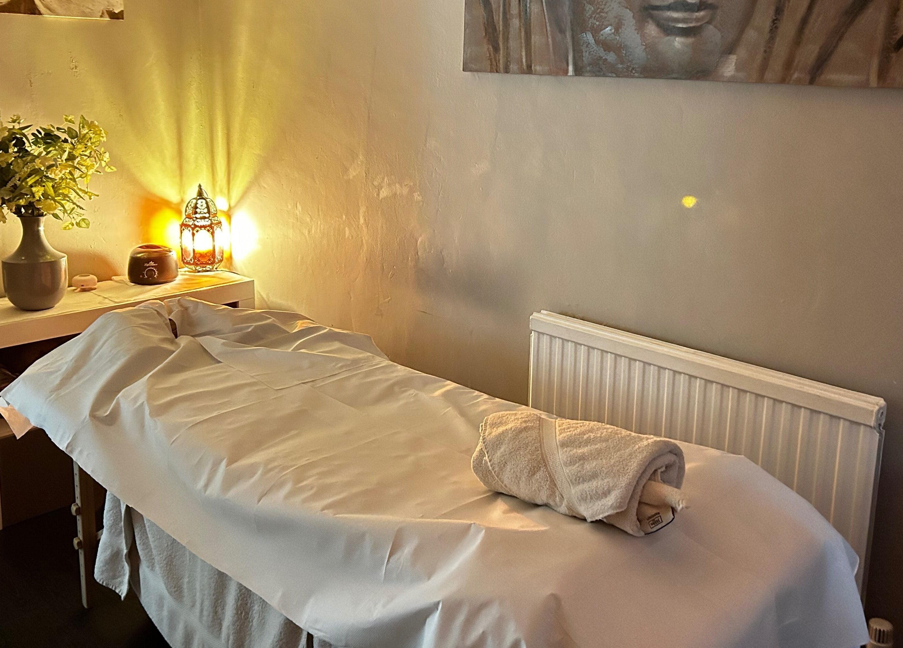 Peaceful massage room at Hands of Buddha, Sale, England, GB with warm lighting and fresh flowers.