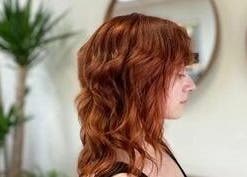 Profile of redhead hairstyle at Cactus Salon, Addison, Texas, US, featuring gentle curls and vibrant color.