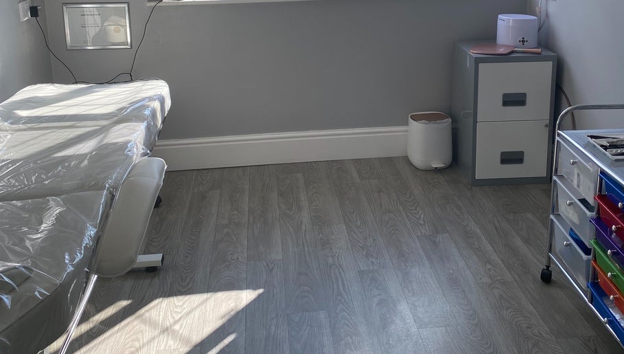 A calm treatment room at Radiant by Julie in Derby, England, GB, featuring a massage table and organized storage.