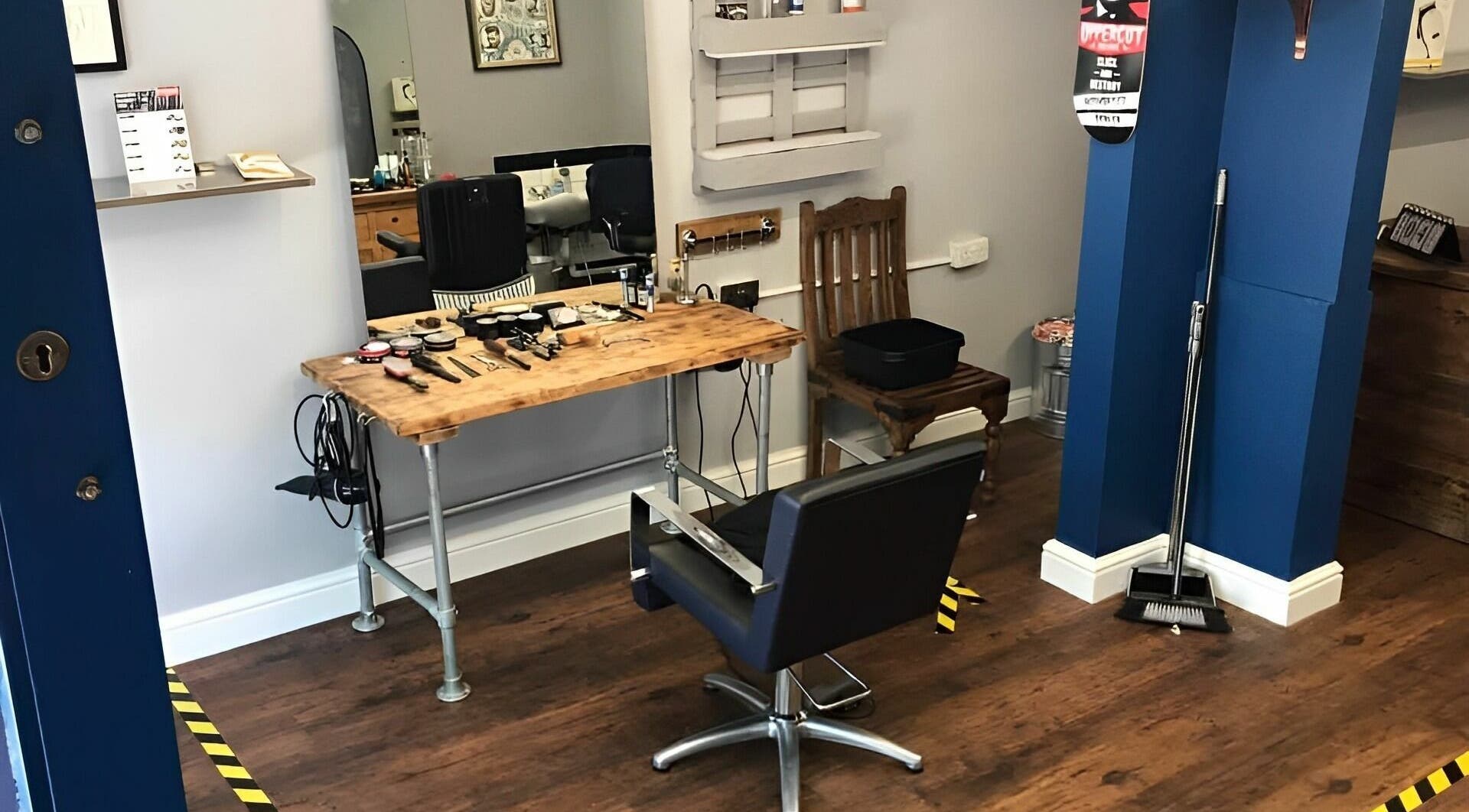 Interior of Gaza’s Barbers in Swindon, England, GB, featuring a stylish barber chair and rustic worktable.