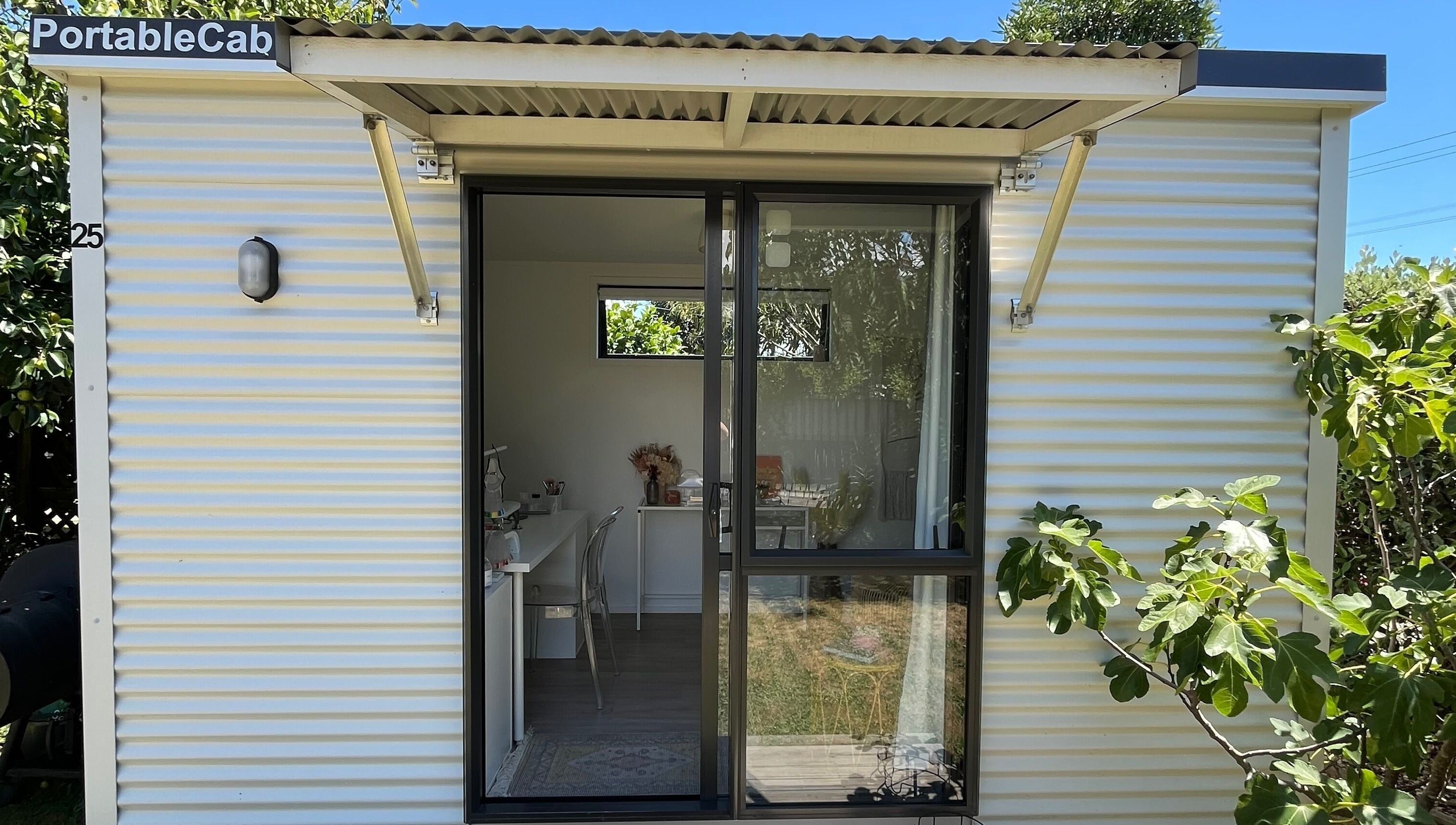 Exterior view of GeLest Nails at Nelson. Bright portable cabin embraced by leafy greens, offering a relaxing atmosphere.