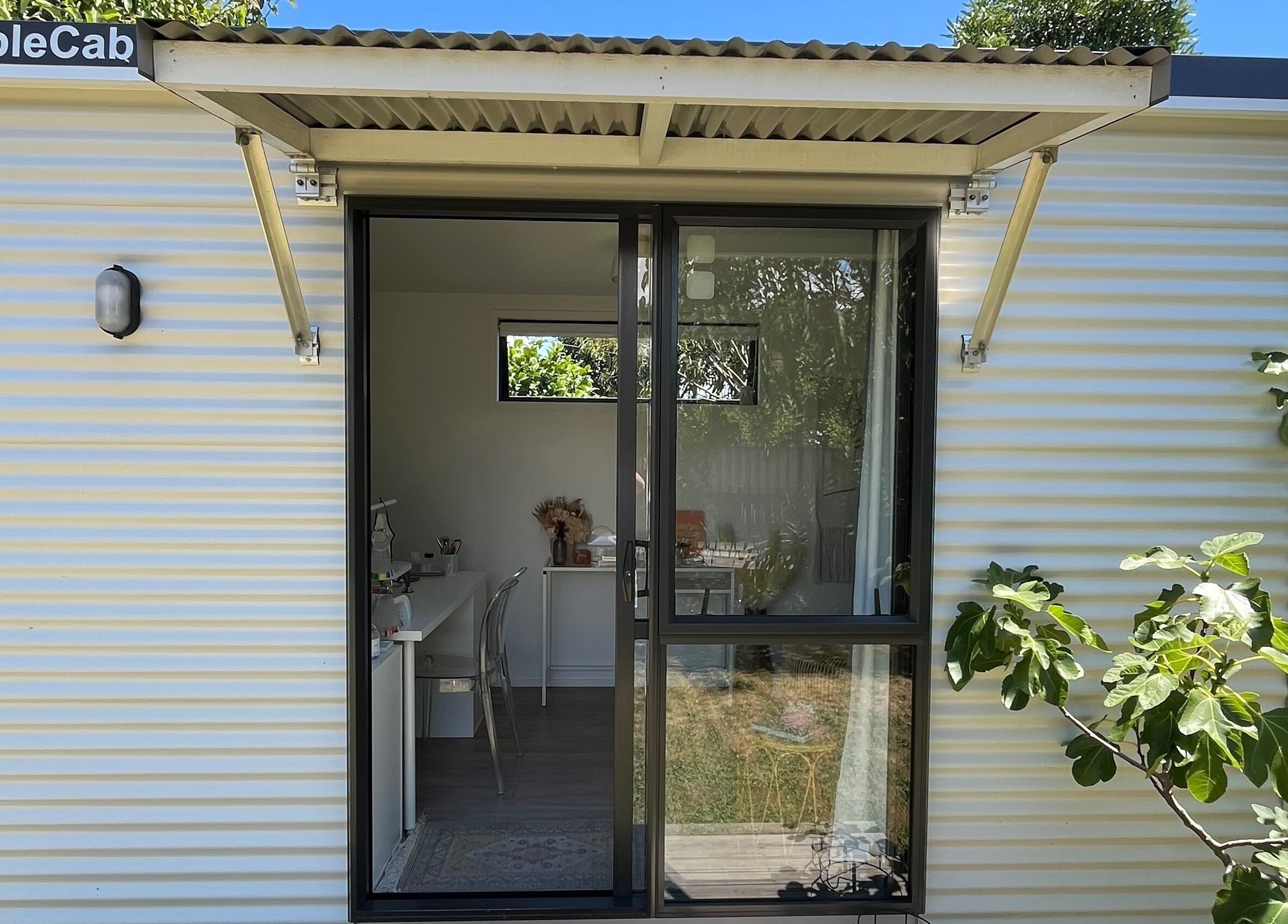 Exterior view of GeLest Nails at Nelson. Bright portable cabin embraced by leafy greens, offering a relaxing atmosphere.