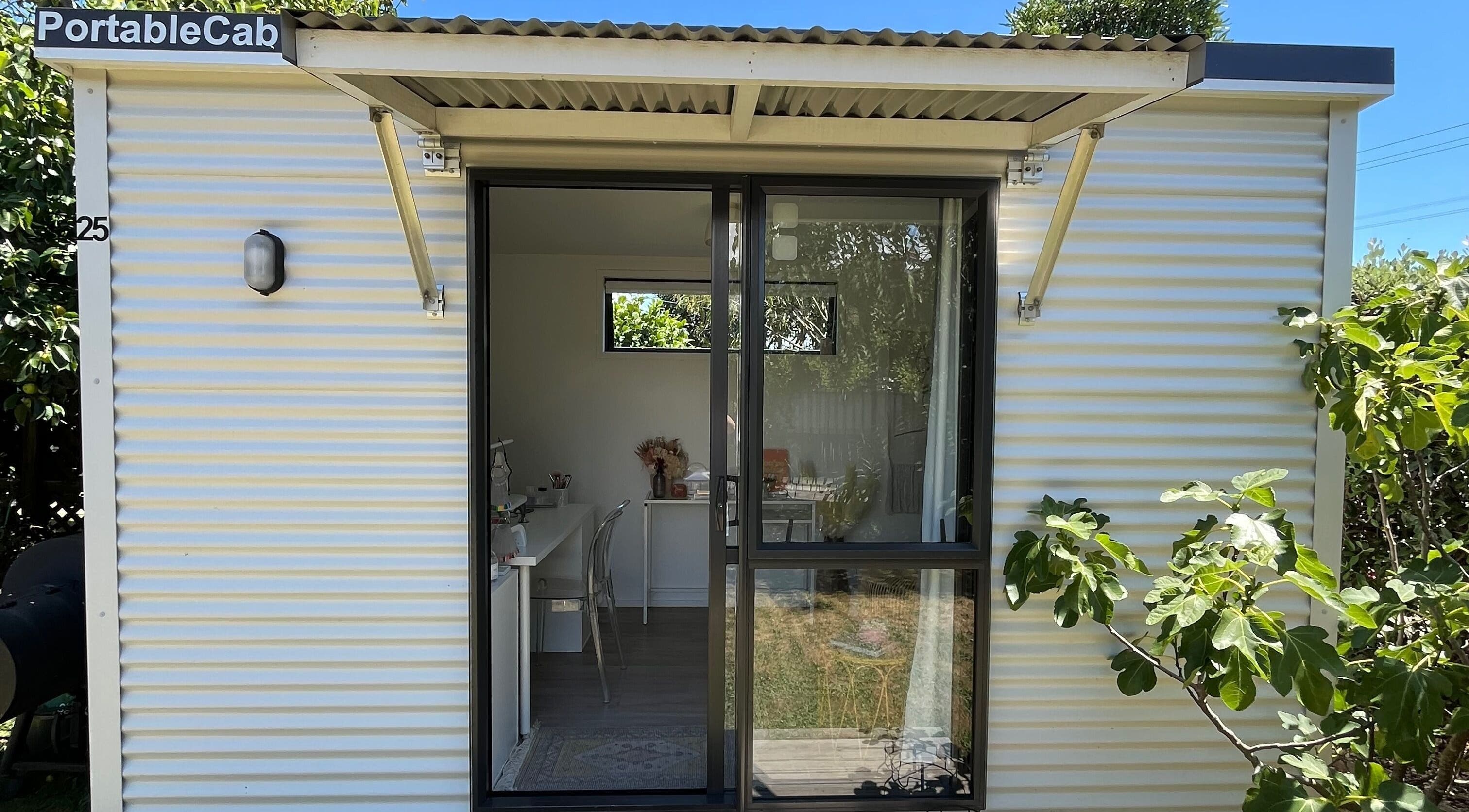 Exterior view of GeLest Nails at Nelson. Bright portable cabin embraced by leafy greens, offering a relaxing atmosphere.