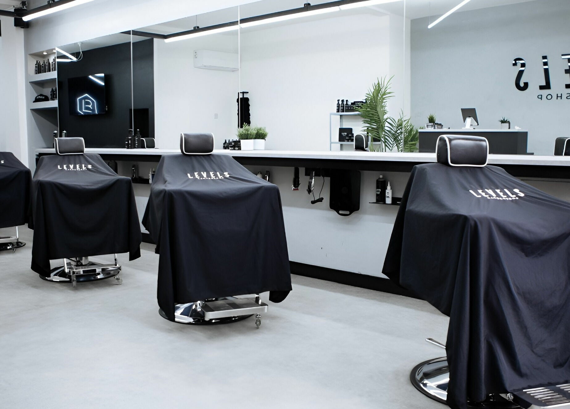 Modern barber chairs in Levels Mens Grooming, Newton Abbot, England, GB, showcasing sleek interior design.