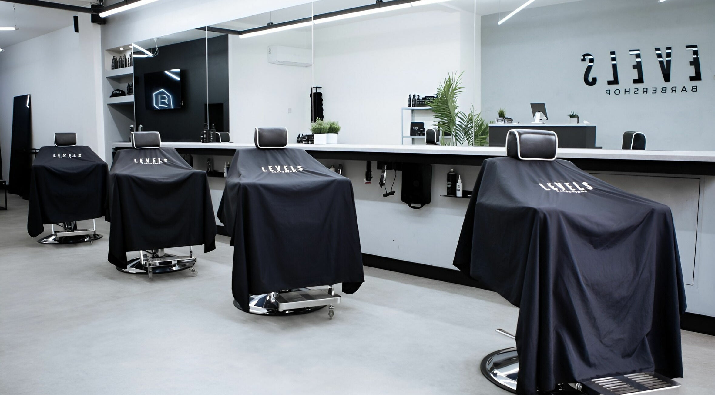 Modern barber chairs in Levels Mens Grooming, Newton Abbot, England, GB, showcasing sleek interior design.