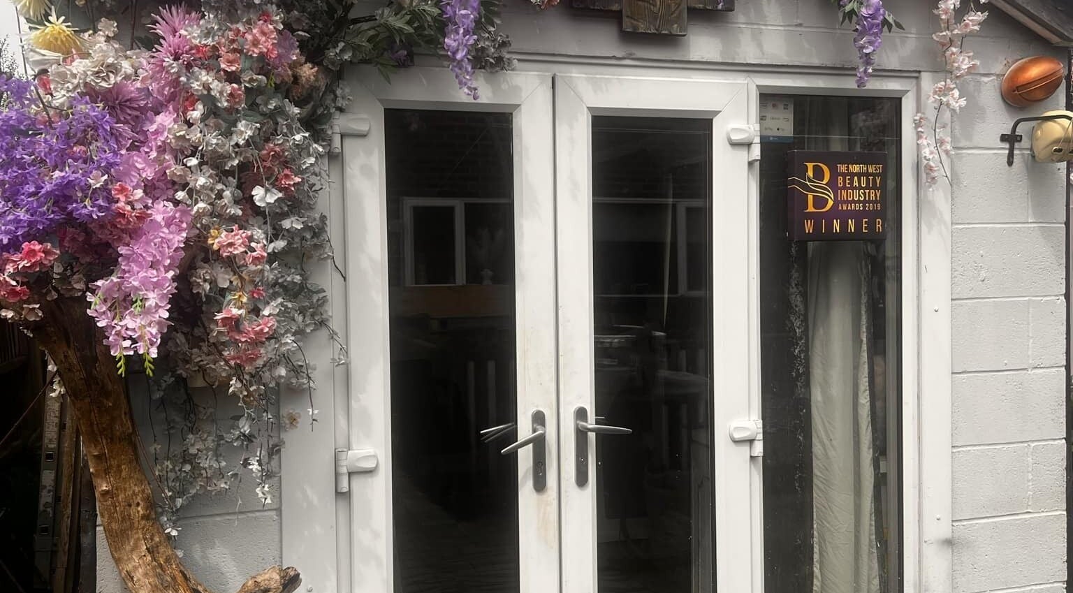Floral-adorned entrance of Meraki Beauty and Aesthetics, Penwortham, England. Award-winning beauty venue.