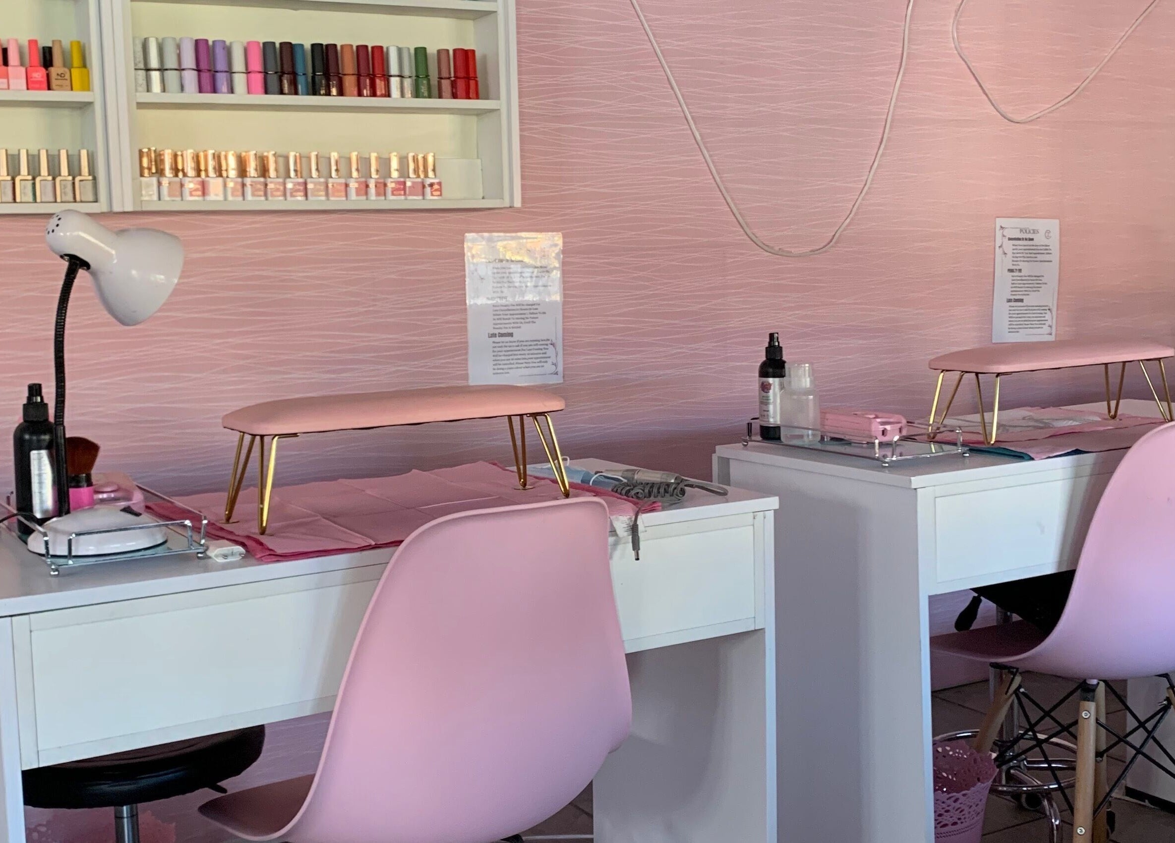 Elegant nail stations at Me Myself And Nails in Soweto, Gauteng, ZA featuring pink seating and nail polish display.