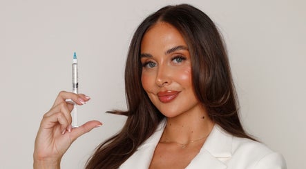 Smiling woman holding a syringe at Skin & Co Aesthetics in Crowthorne, England, GB, highlighting skincare expertise.