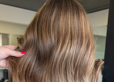 Luxurious brown hair styled at Hair by Karina Brown in Leeds, England, GB, highlighted by a vibrant pink nail.