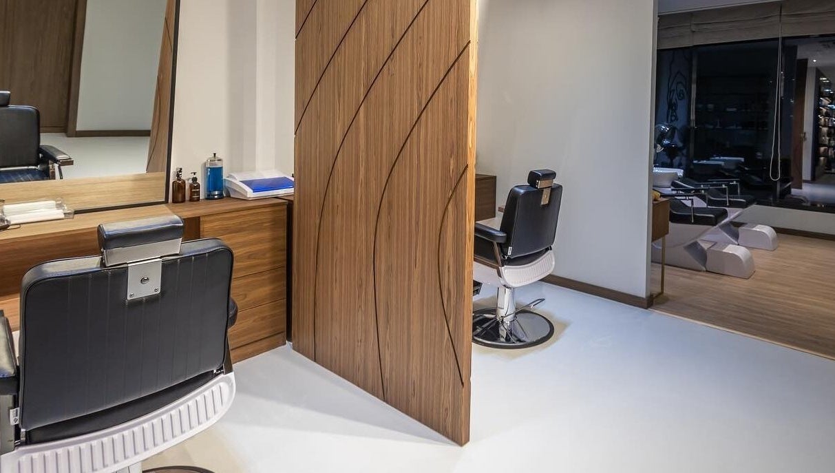 Modern salon interior at Antibes Salon Seef, Manama, BH, showcasing sleek styling chairs and warm wood decor.