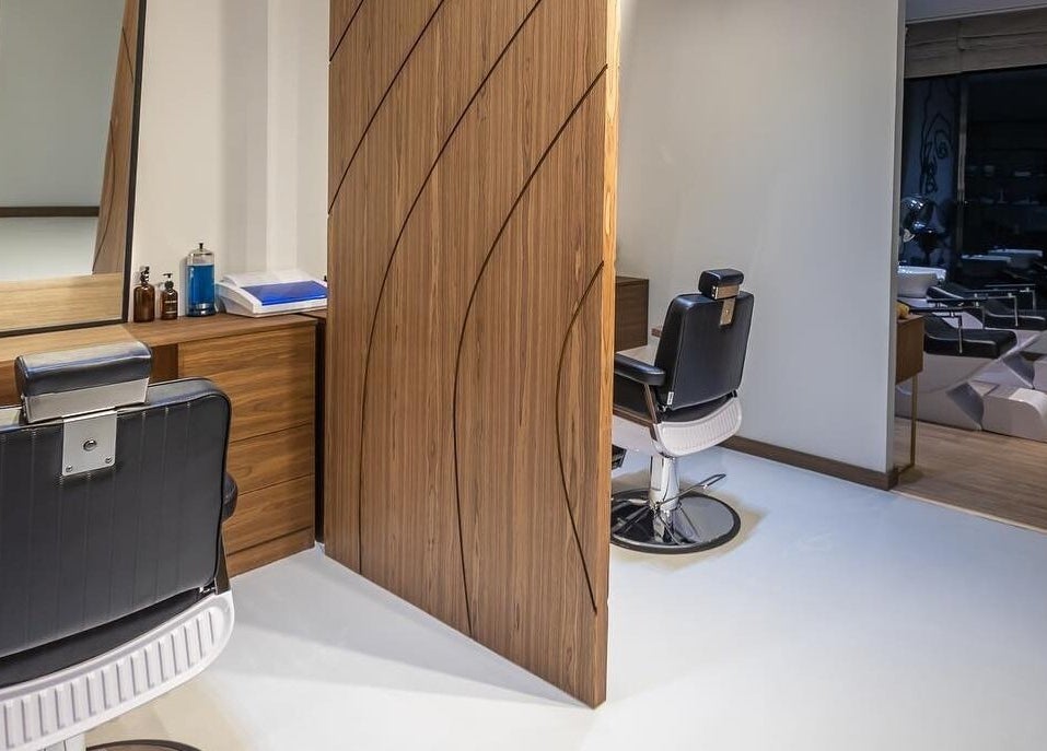 Modern salon interior at Antibes Salon Seef, Manama, BH, showcasing sleek styling chairs and warm wood decor.