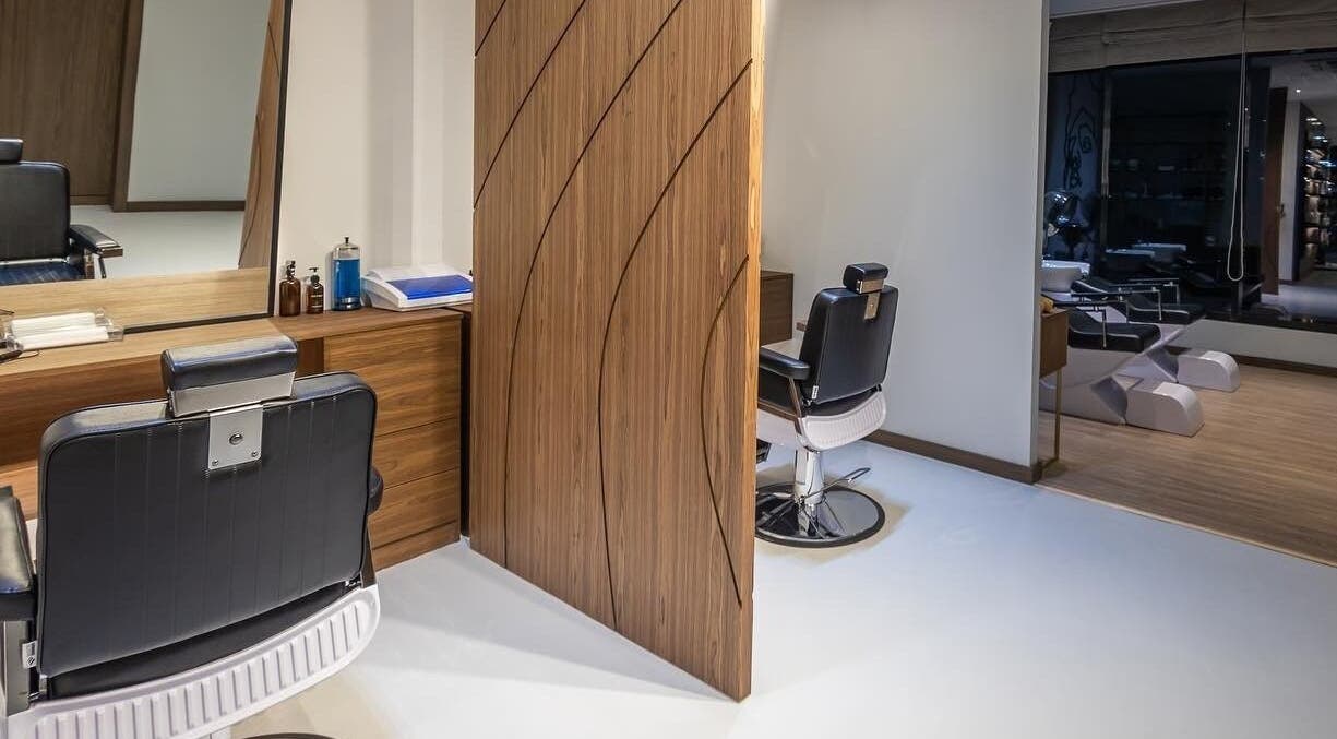 Modern salon interior at Antibes Salon Seef, Manama, BH, showcasing sleek styling chairs and warm wood decor.