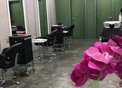Stylish interior of Color Cravings Beauty Salon in Bu Quwah, with modern chairs and vibrant orchids.