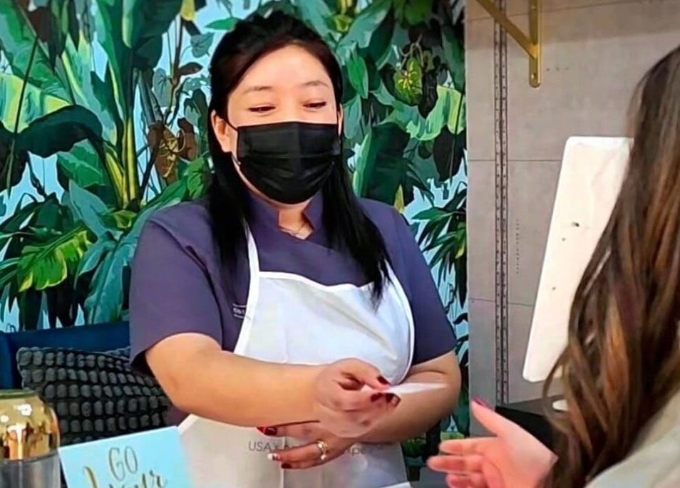 Receptionist at Color Cravings Beauty Salon, Bu Quwah, Northern Governorate, BH, greets a client warmly.