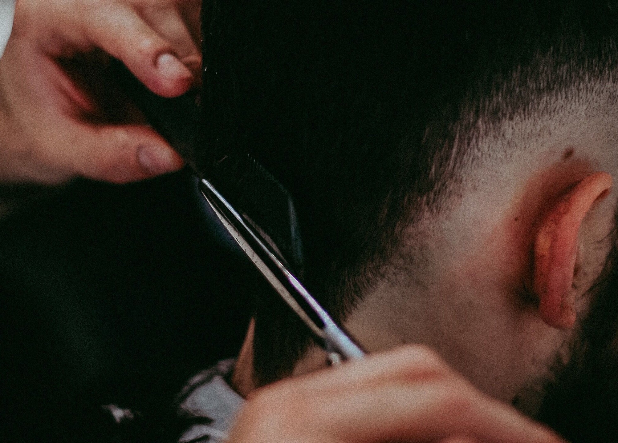 Taglio di capelli maschile al Barber Lounge, Milano, Lombardia, IT, utilizzando un pettine e forbici.