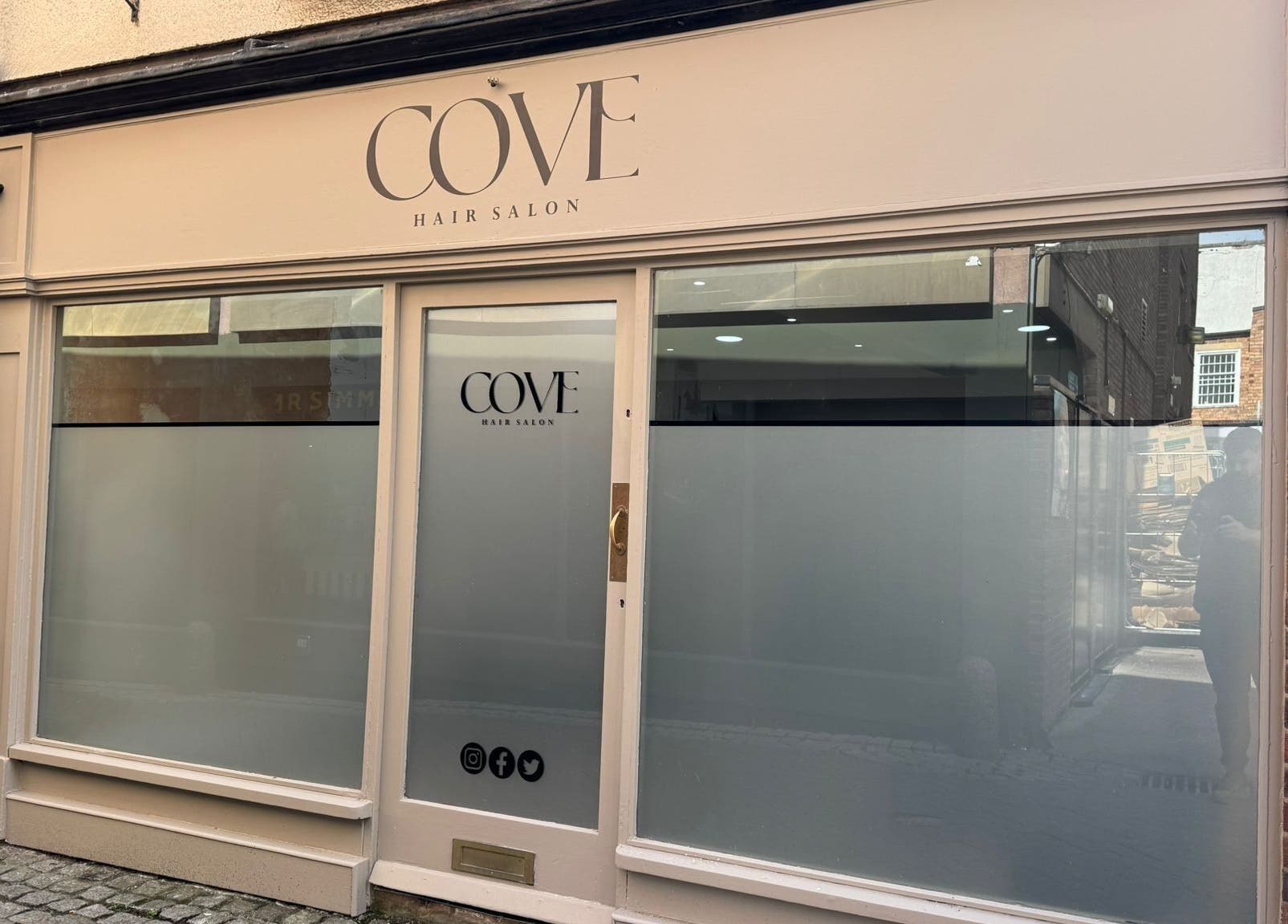 Front view of Cove Hair Salon in Stafford, England featuring minimalist design and large windows.