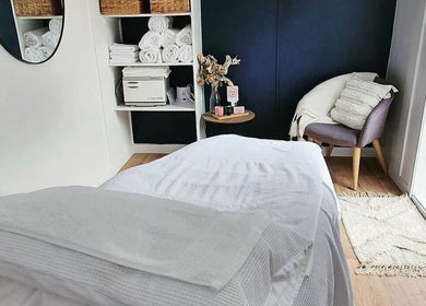 Tranquil spa room at The Beauty Loft, Waihi Beach, Bay Of Plenty, NZ with cozy chair and soft linens.
