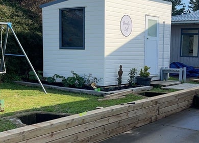 Charming garden at The Beauty Loft, Waihi Beach, Bay Of Plenty, NZ, with modern white exterior and plants.