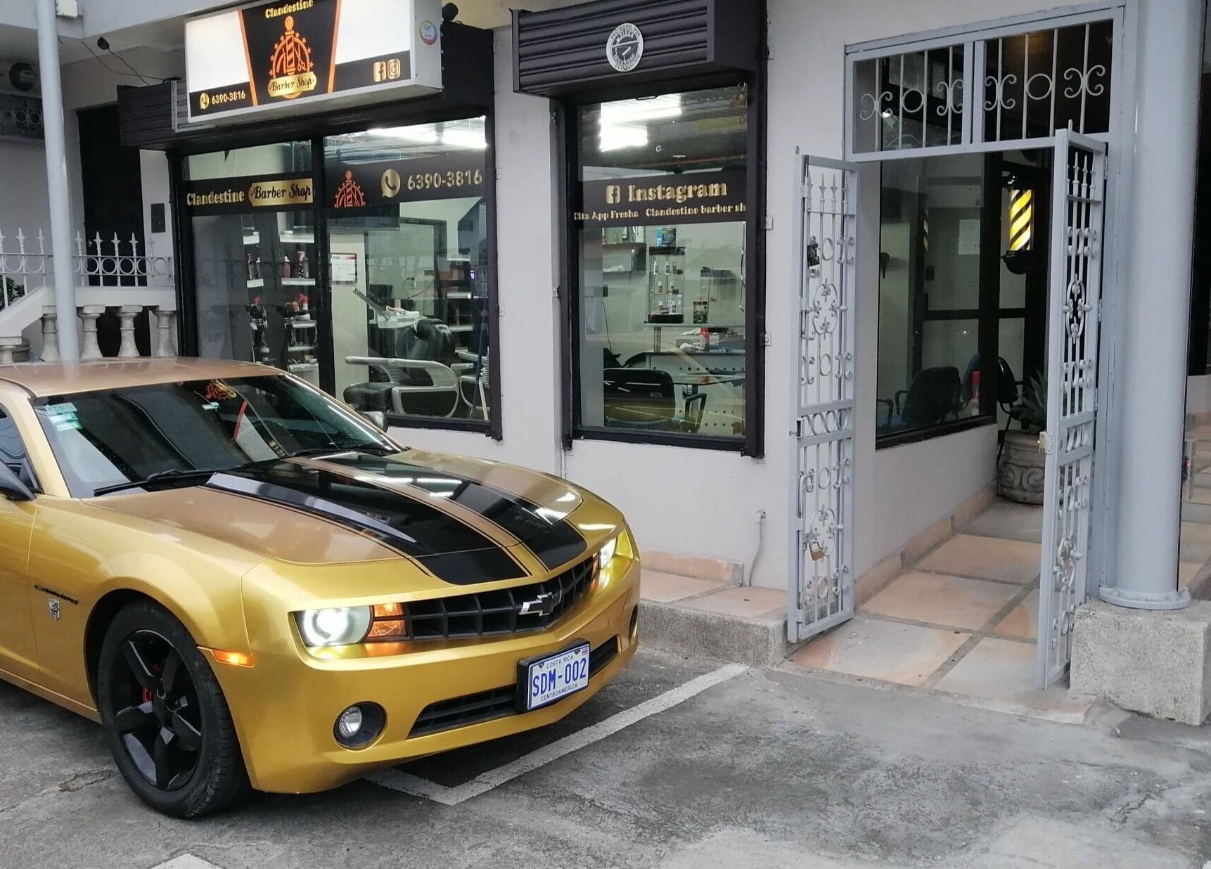 Coche dorado frente a Clandestine Barber Shopvip001 en San Vicente, San José, CR.