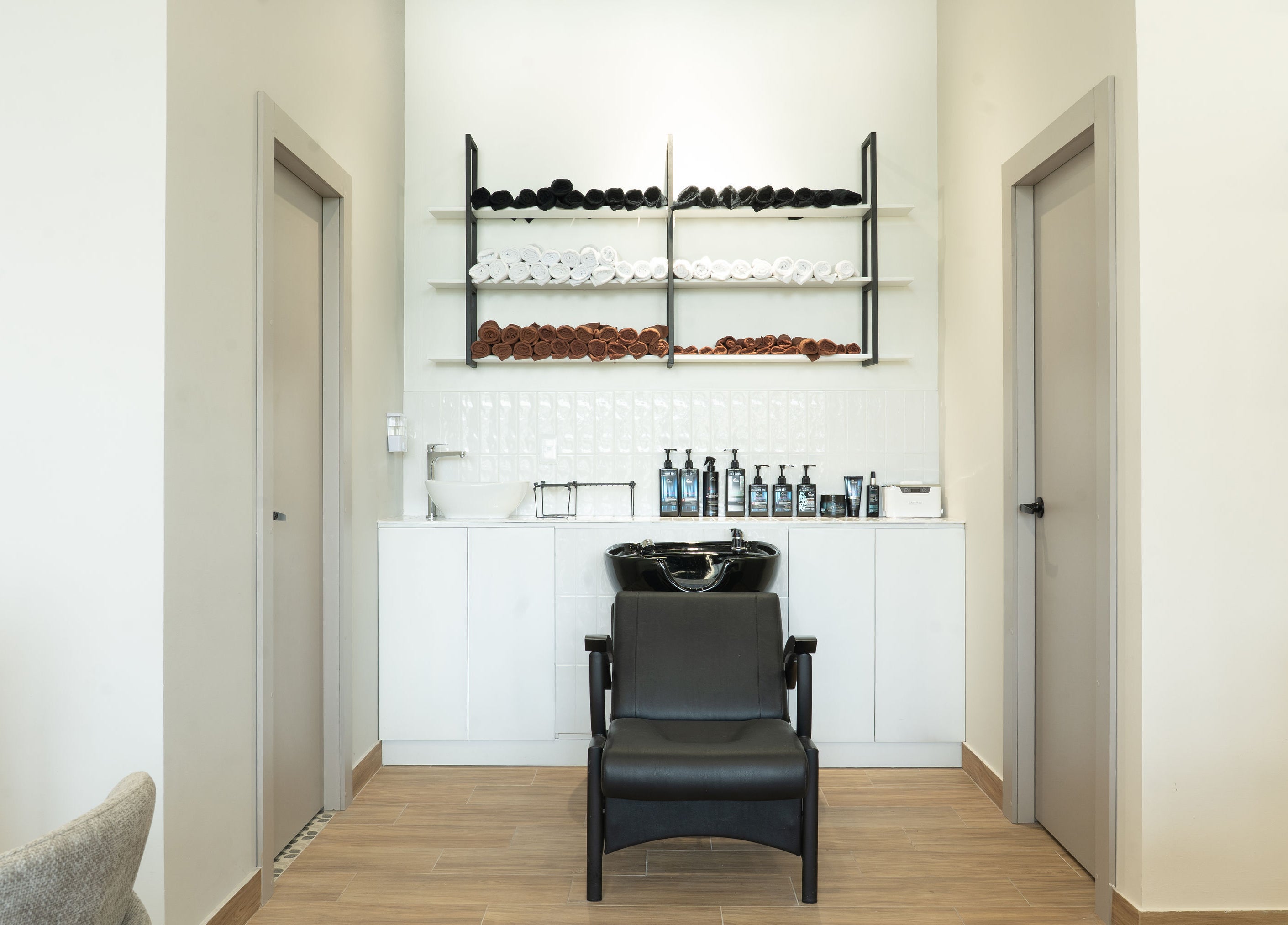 Zona de lavado elegante en The Nail Kitchen Villa Club, Daule, Guayas, EC con sillas negras y estantes organizados.