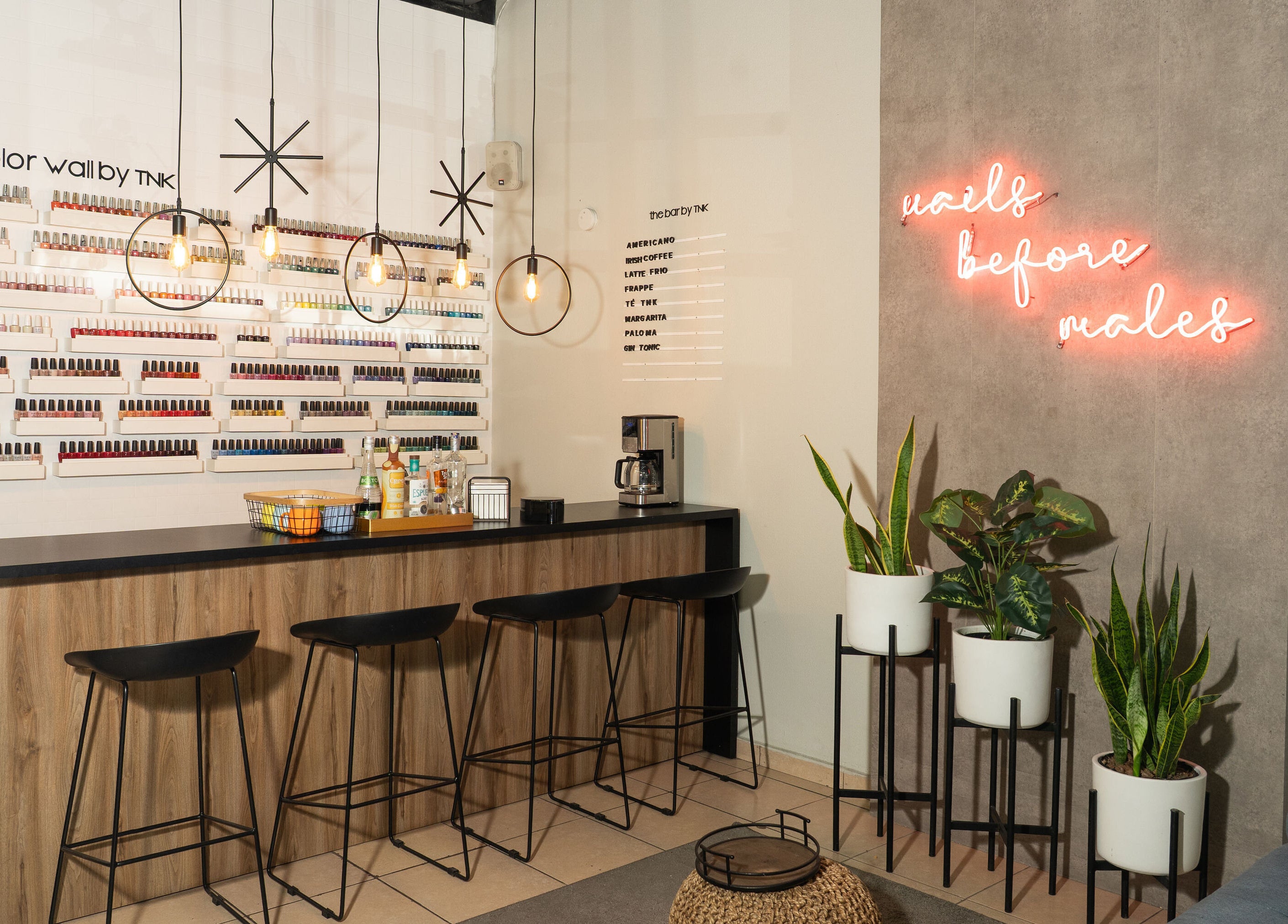 Interior de The Nail Kitchen Samborondón, Guayas, EC, con pared de esmaltes y barra de bebidas.