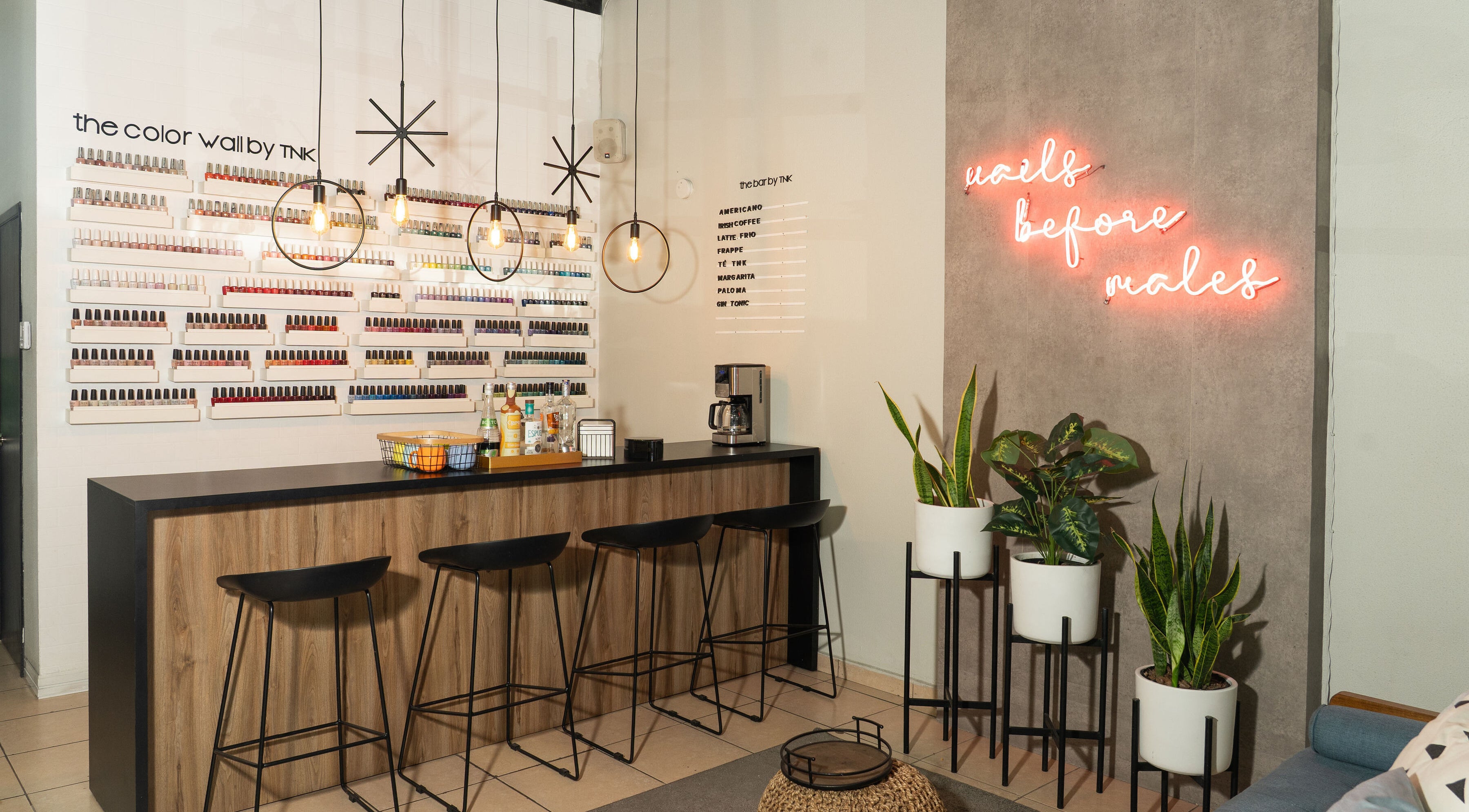 Interior de The Nail Kitchen Samborondón, Guayas, EC, con pared de esmaltes y barra de bebidas.