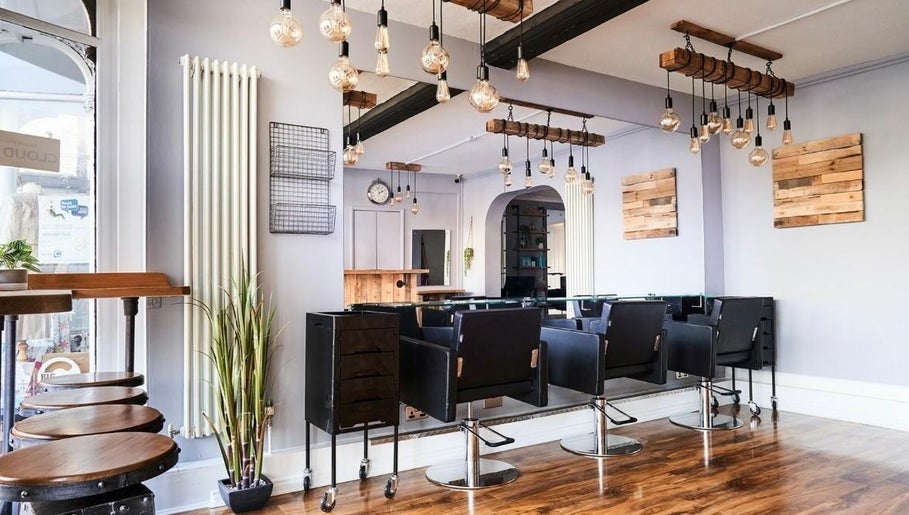 Modern salon interior at The Ultimate Touch in Wymondham, England, GB, featuring sleek chairs and rustic decor.