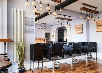 Modern salon interior at The Ultimate Touch in Wymondham, England, GB, featuring sleek chairs and rustic decor.