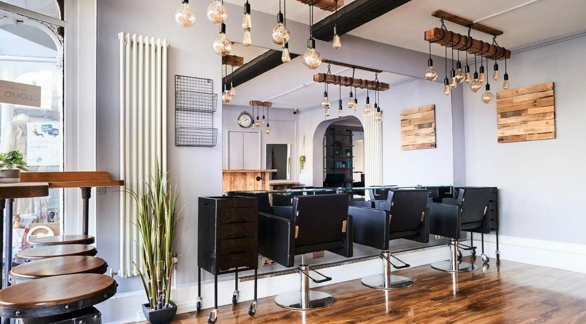 Modern salon interior at The Ultimate Touch in Wymondham, England, GB, featuring sleek chairs and rustic decor.