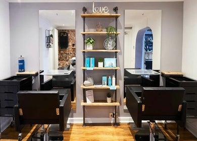 Modern salon interior at The Ultimate Touch, Wymondham, England, GB, featuring stylish chairs and shelving decor.