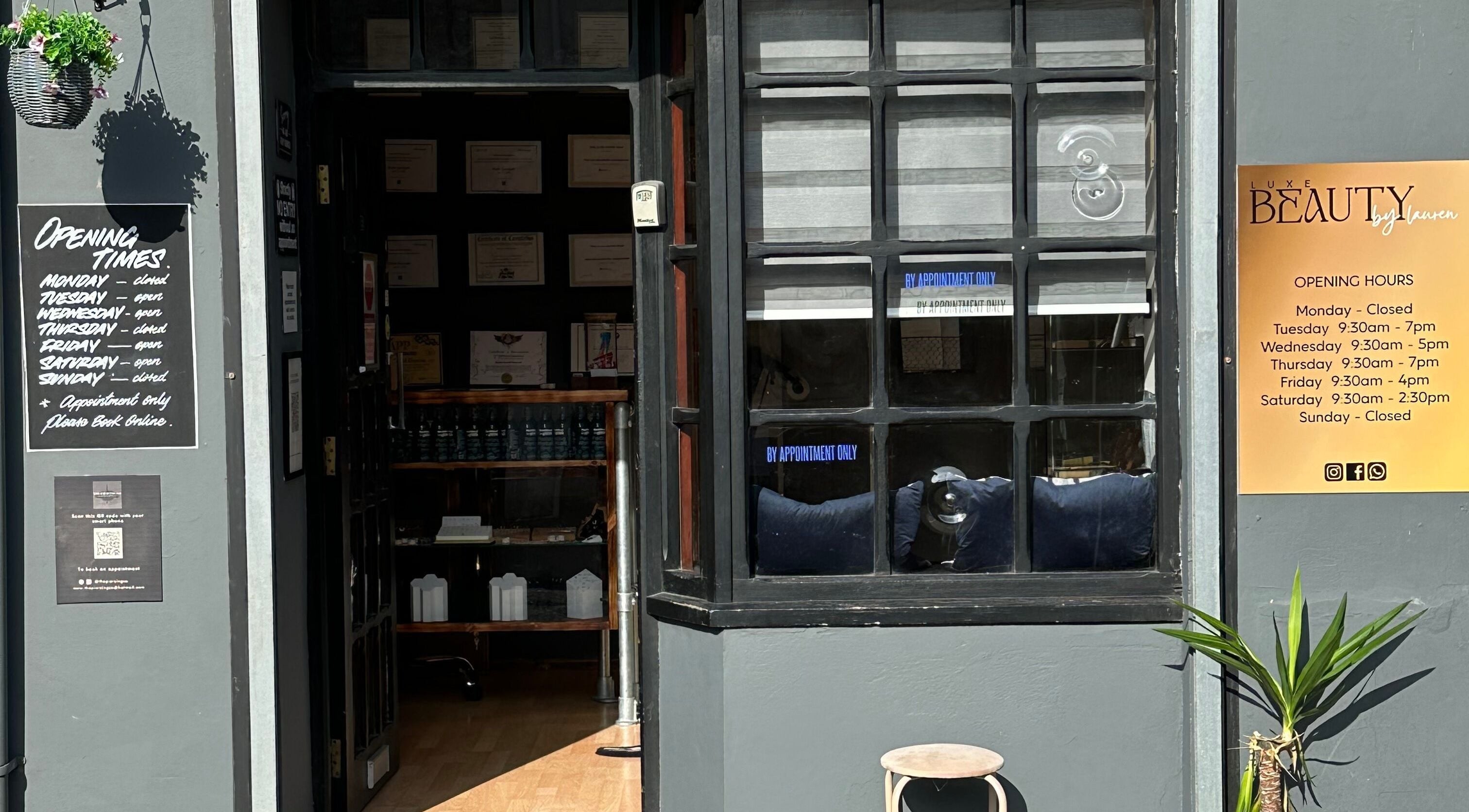 Entrance of The Piercing Co in Bridgend, Wales, GB, featuring opening hours sign and modern decor.