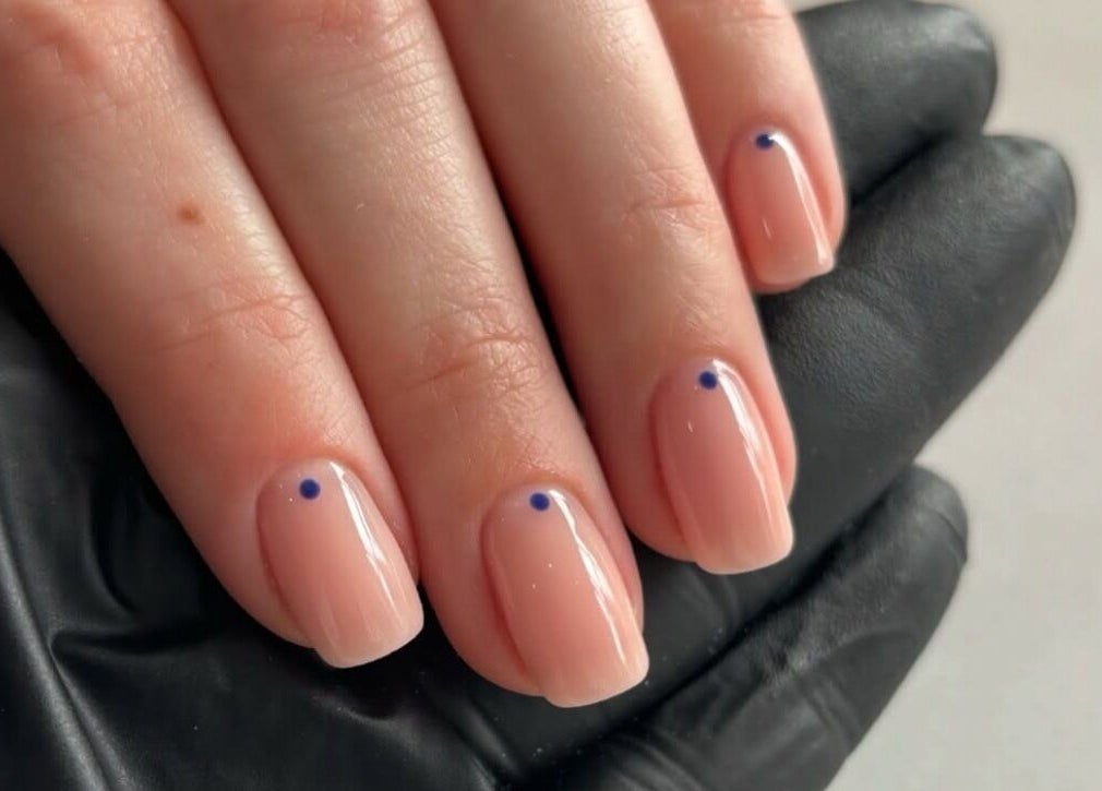 Manicured hand with minimalist blue dot design by Beckie Wilson Manicurist in Howden, England, GB.