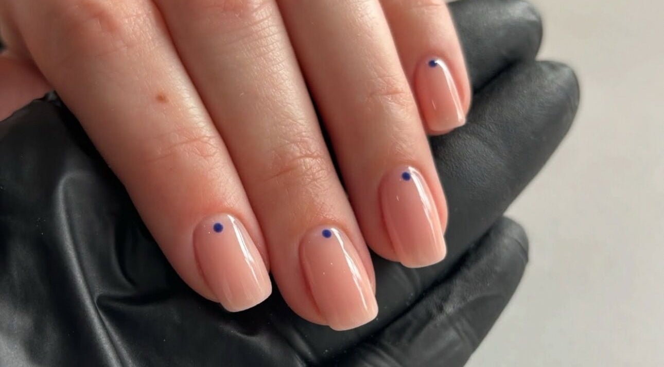 Manicured hand with minimalist blue dot design by Beckie Wilson Manicurist in Howden, England, GB.