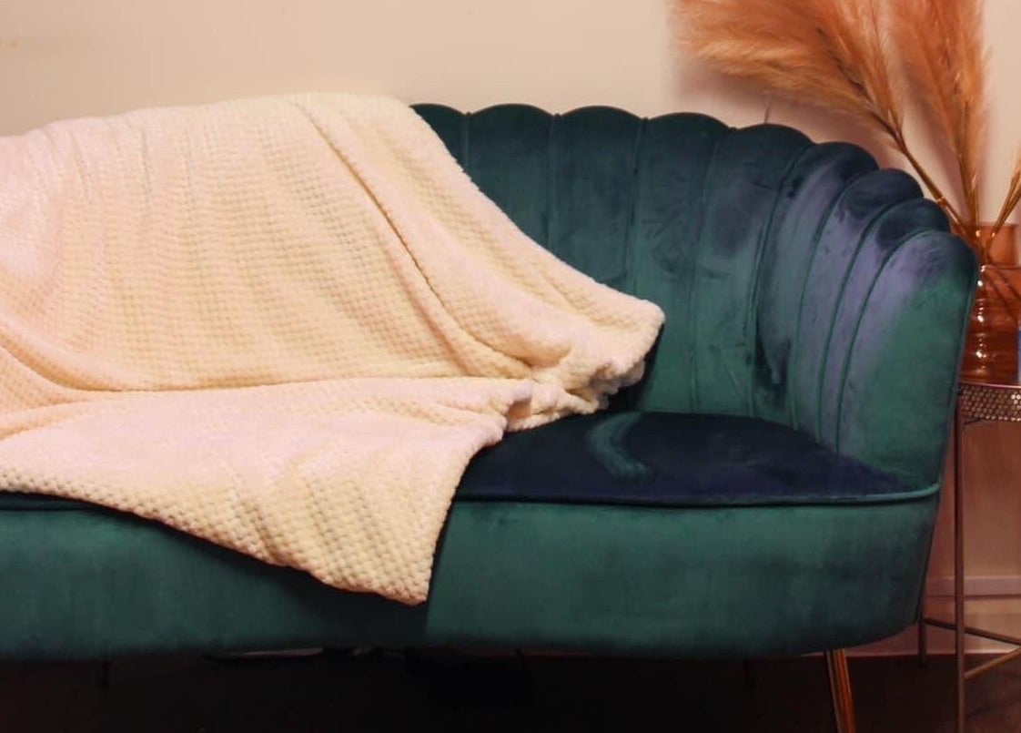 Elegant teal sofa with cozy blanket at Glow Beauty, Redhill, England, GB.