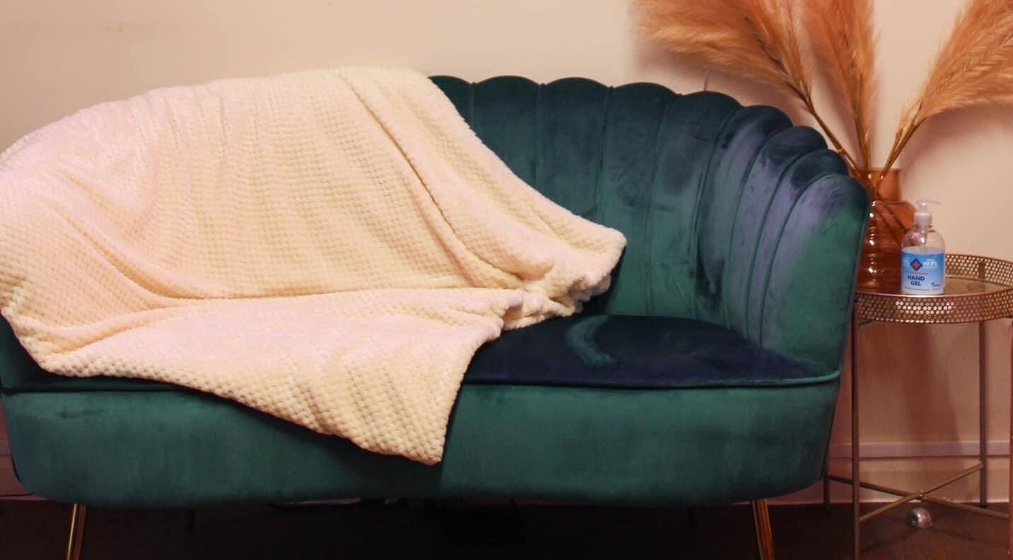 Elegant teal sofa with cozy blanket at Glow Beauty, Redhill, England, GB.