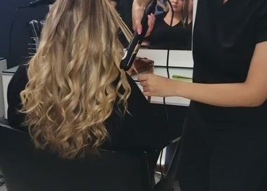 Hair stylist curling hair at Hadassah Aesthetic Hair and Beauty Clinic, Upington, Northern Cape, ZA.