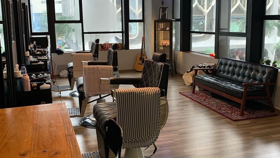 Stylish interior of Envy Cuts in Singapore, featuring chic barber chairs and cozy seating area.