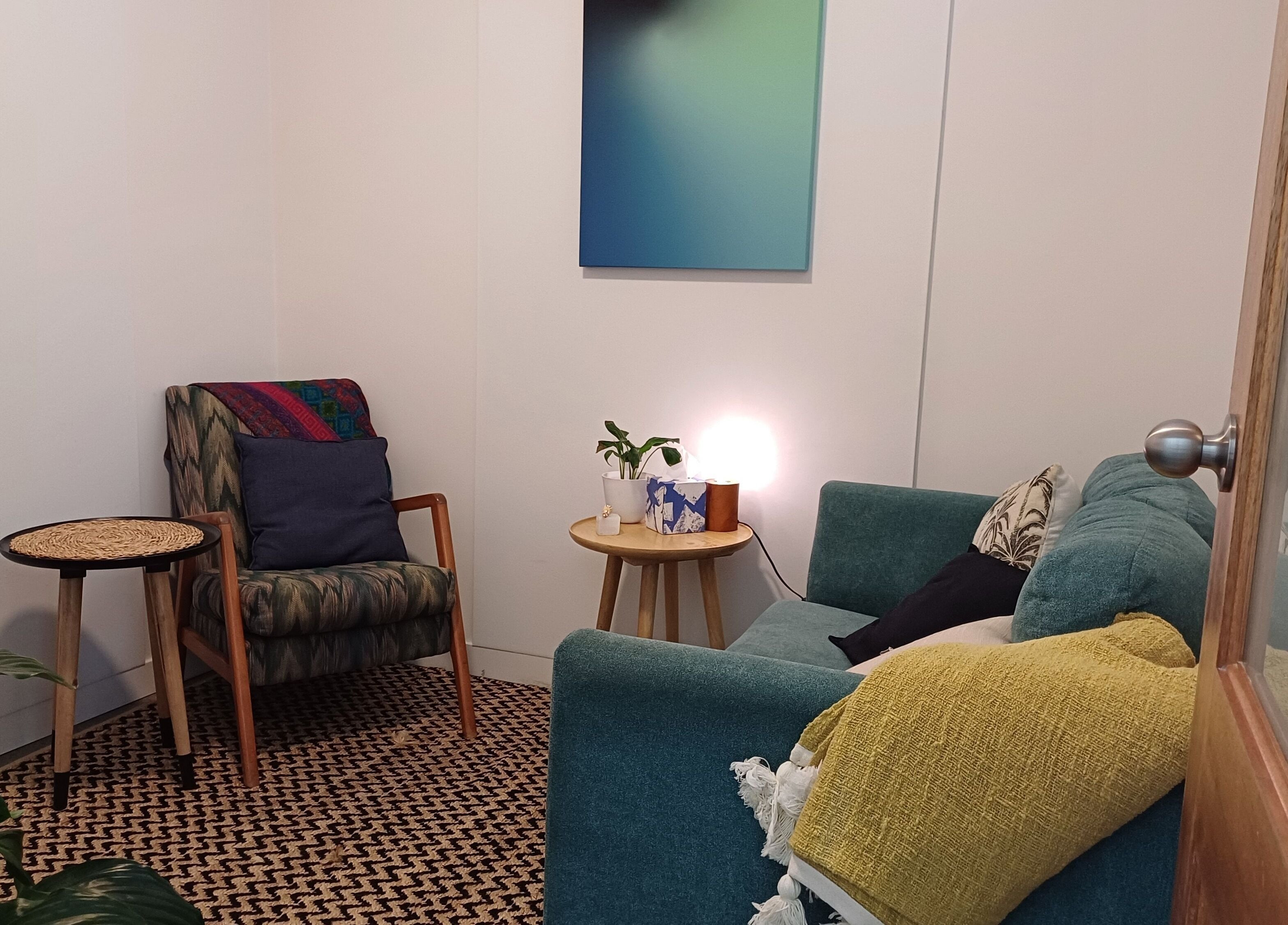 Relaxing therapy room at Sacred Ground Australia, Palm Beach, Queensland, AU with chairs, cushions, and warm lighting.