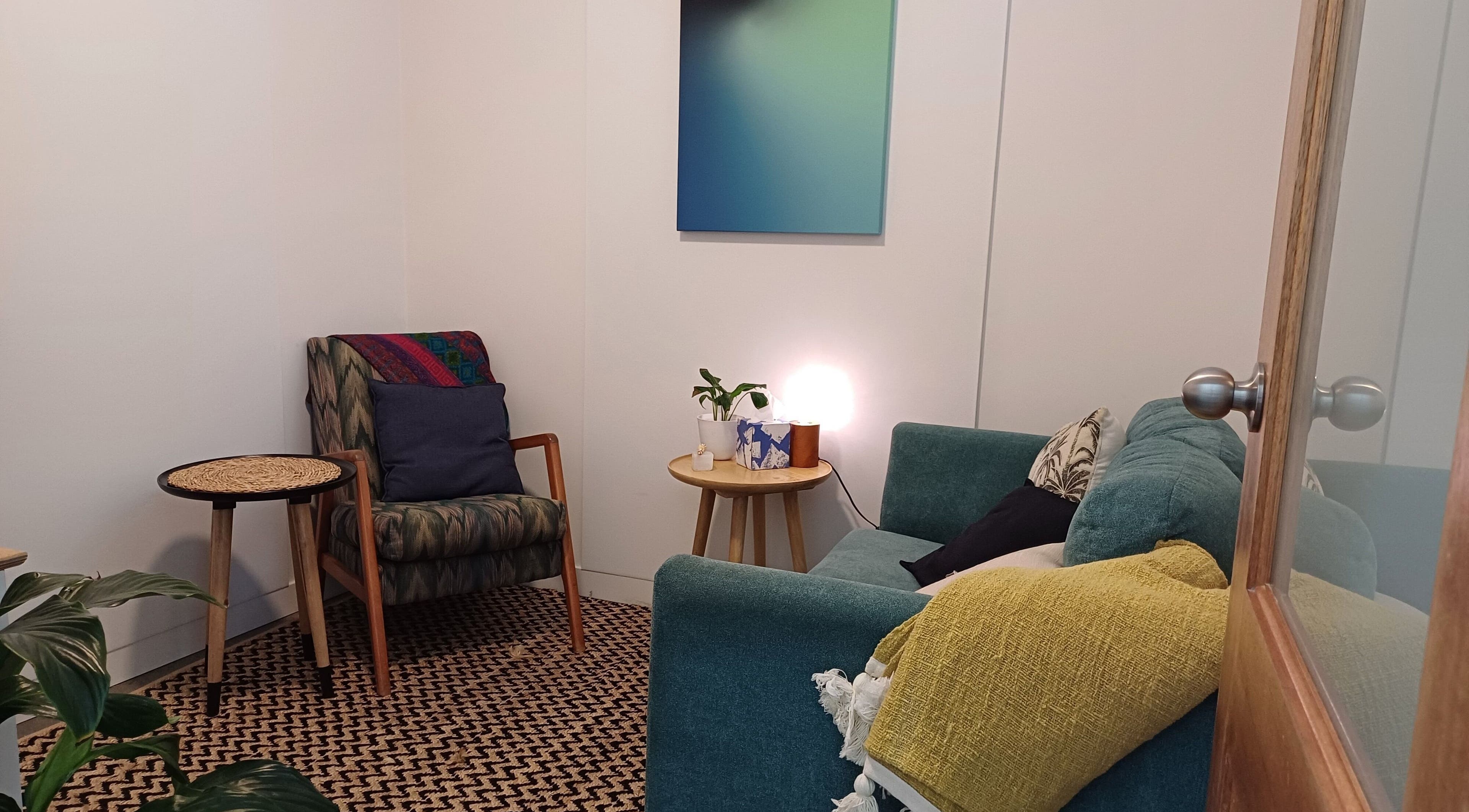 Relaxing therapy room at Sacred Ground Australia, Palm Beach, Queensland, AU with chairs, cushions, and warm lighting.