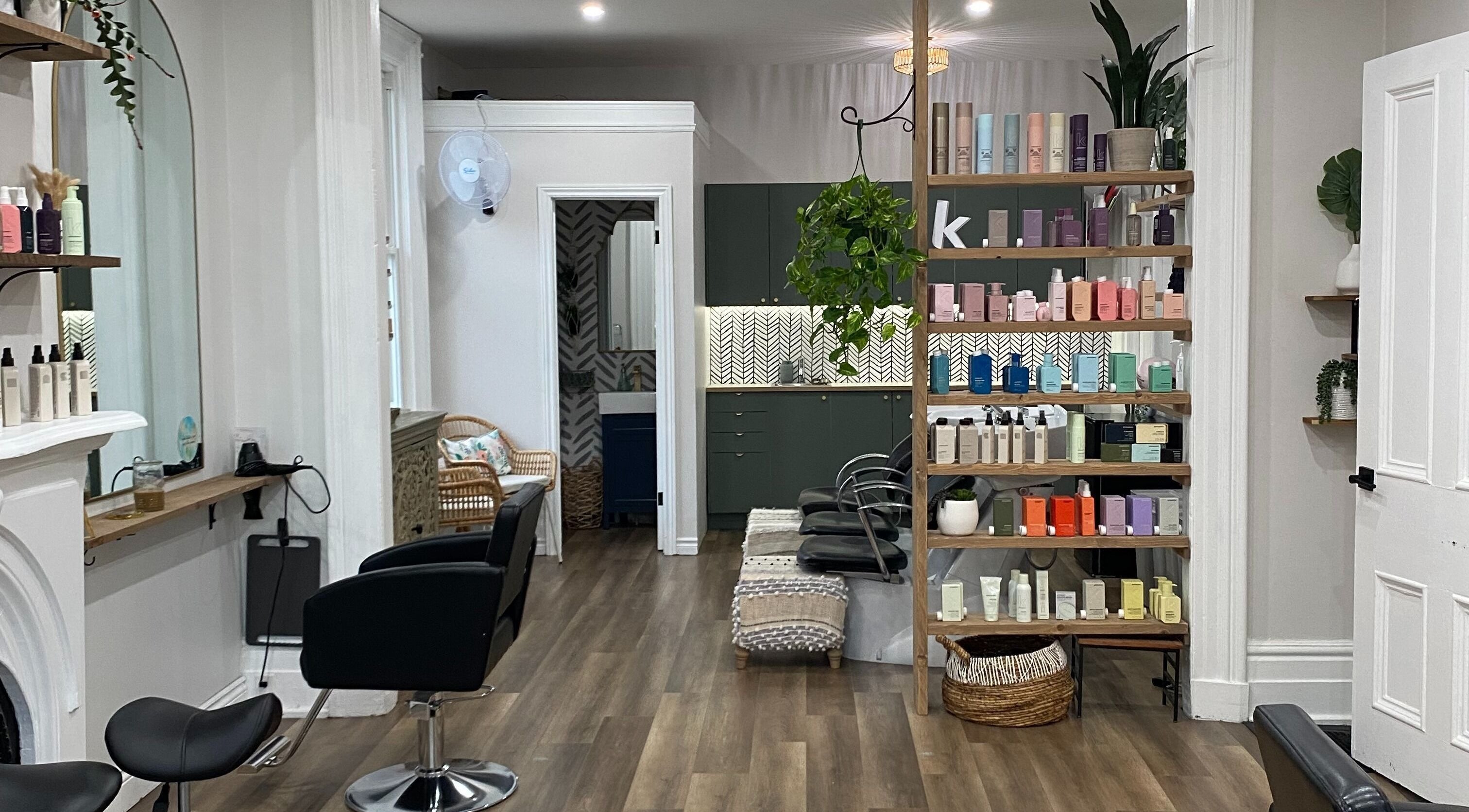 Inside Rehab Hair Studio, Orangeville, Ontario, CA; stylish salon chairs and chic shelving display products beautifully.