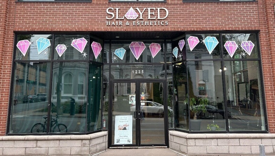 Front view of Slayed Hair And Esthetics in Halifax, Nova Scotia, CA with stylish glass door and gemstone decor.